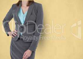 Midsection of businesswoman standing with hand on hip against yellow background