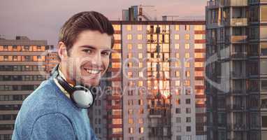 Smiling hipster with headphones against buildings