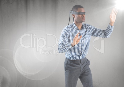 Business man blindfolded with flare and grunge overlay against grey background
