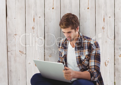 Businessman using laptop against wooden wall