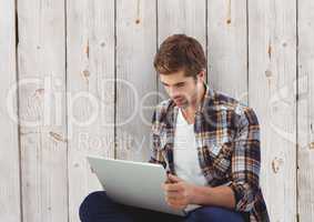Businessman using laptop against wooden wall