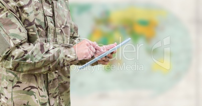 Soldier mid section with tablet against blurry map