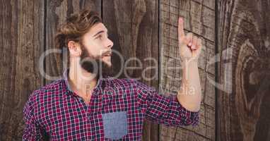 Male hipster pointing upwards against wooden wall