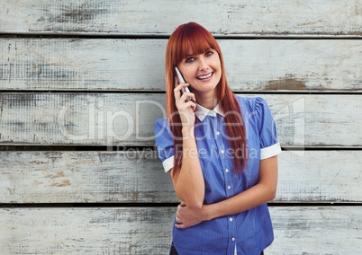 Redhead woman using mobile phone over wooden wall