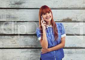Redhead woman using mobile phone over wooden wall