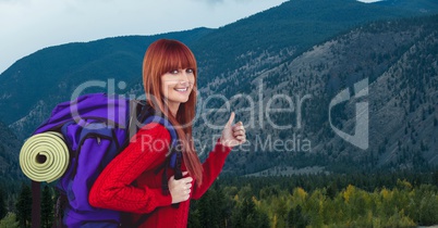 Portrait of happy female traveler showing thumbs up against mountain