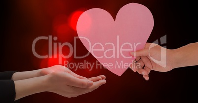 Hand giving heart shape to woman against red bokeh