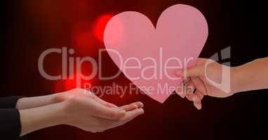 Hand giving heart shape to woman against red bokeh