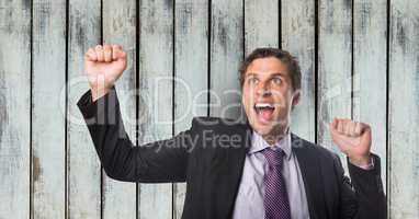 Happy businessman celebrating success over wooden wall
