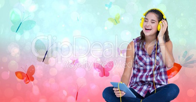 Happy female listening to music through headphones using tablet PC over butterfly background
