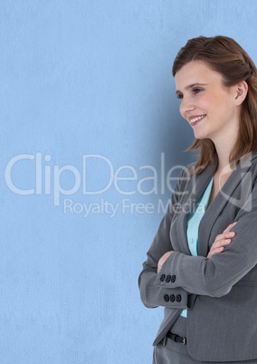 Happy thoughtful businesswoman standing arms crossed against blue background