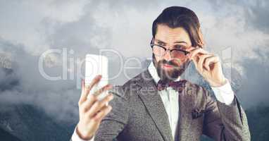 Hipster wearing eyeglasses while reading message on smart phone