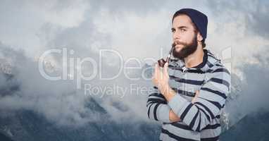 Confident hipster smoking pipe against mountains