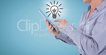 Business woman with tablet and lightbulb doodle with flare against blue background