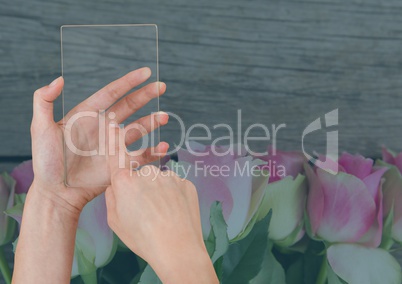 Hand holding a glass tablet with flowers
