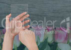 Hand holding a glass tablet with flowers