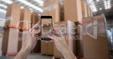 Hands photographing boxes through smart phone in warehouse