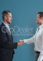 Side view of businessmen shaking hands against blue background