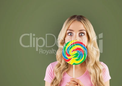 Surprised woman with lollipop over green background