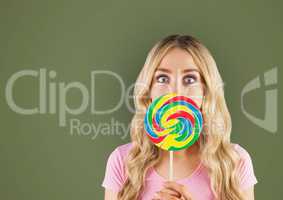 Surprised woman with lollipop over green background
