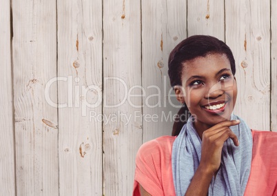 Thoughtful female hipster smiling against wooden wall