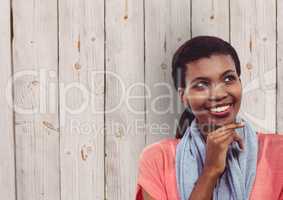 Thoughtful female hipster smiling against wooden wall