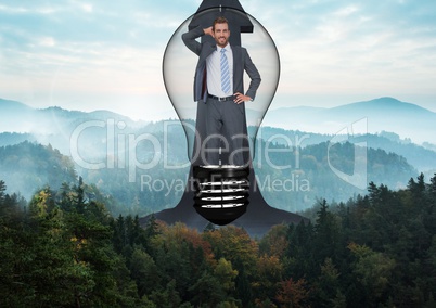 Businessman in light bulb over road against mountains