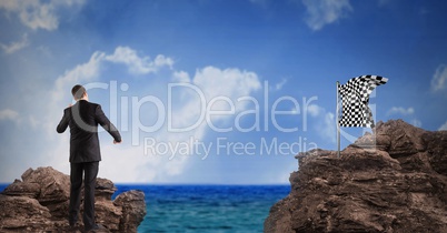 Businessman looking at checked flag on rock against sky