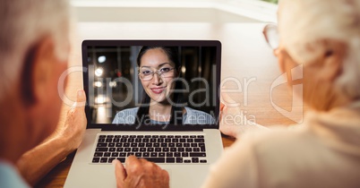 Rear view of senior couple having video conference with woman on laptop
