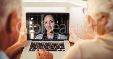Rear view of senior couple having video conference with woman on laptop