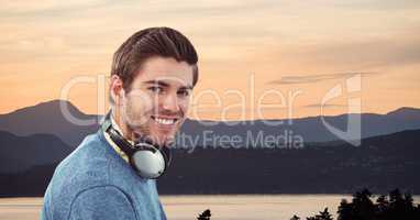 Smiling man wearing headphones against mountains