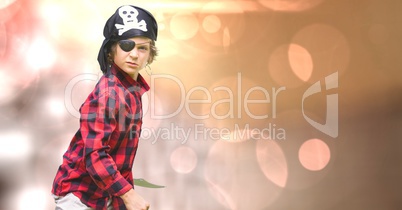 Confident boy in pirate costume standing over bokeh