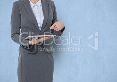 Midsection of businesswoman pointing at tablet PC over blue background