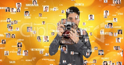 Confident male photographer holding camera surrounded with flying portraits