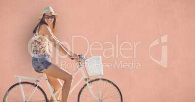 Young woman riding bicycle over colored background
