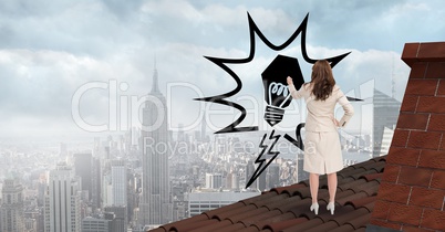 Rear view of businesswoman on roof drawing light bulb in midair