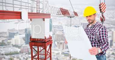 Male architect holding blue print by crane at construction site