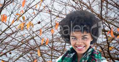Smiling woman with frizzy hair against autumn branches
