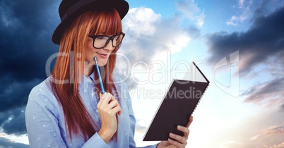 Redhead woman reading book against sky