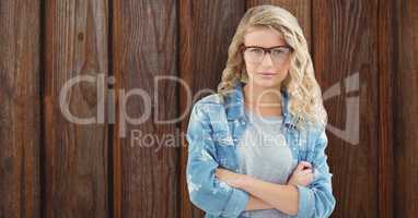 Portrait of confident female hipster standing arms crossed against wooden wall