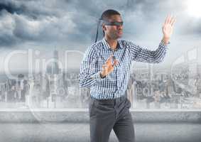 Business man blindfolded with flare against skyline and grey clouds