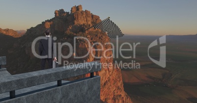 Businessman in the corner of a bridge looking the checker flag in the mountain