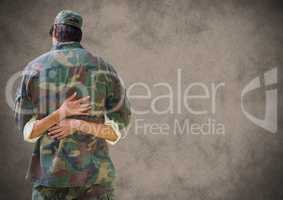Back of soldier hugging with grunge overlay against brown background