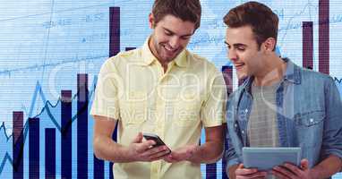 Smiling businessmen holding mobile phone and tablet PC against graphs