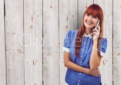 Redhead woman using smart phone over wooden wall