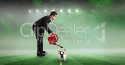 Digital composite image of businessman watering female employees at stadium