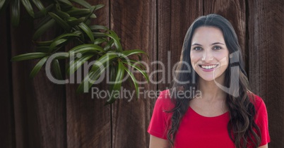 Woman smiling by branch against wooden wall