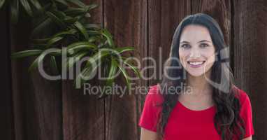 Woman smiling by branch against wooden wall