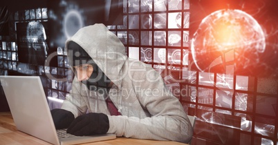 Digital composite image of hacker using laptop at desk