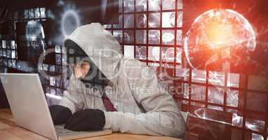 Digital composite image of hacker using laptop at desk